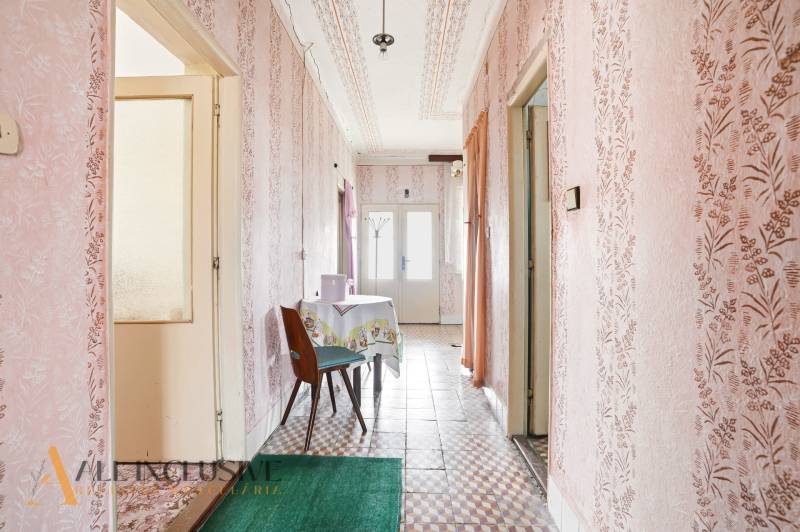 A hallway in a family house with patterned wallpaper and tiles, a table with a tablecloth.