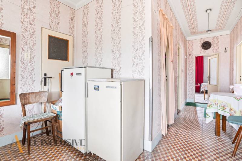 A hallway with a refrigerator and decorative wallpaper in a country family house.