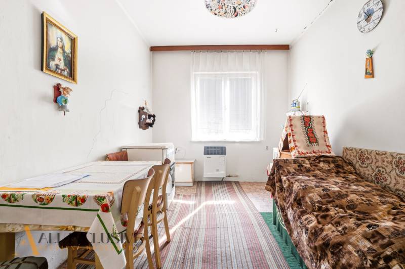 A room in a family house with a bed, a kitchen table, and wall decorations.
