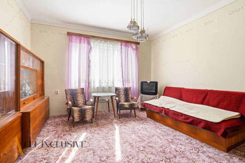 Living room in a family house with older furniture, a television, and a patterned carpet.