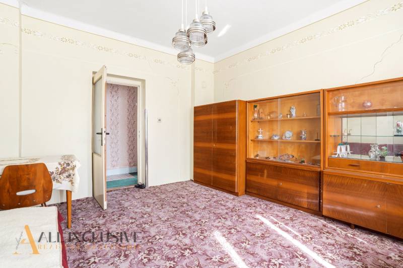 A room in a family house with display cabinets, a table, and a patterned carpet.