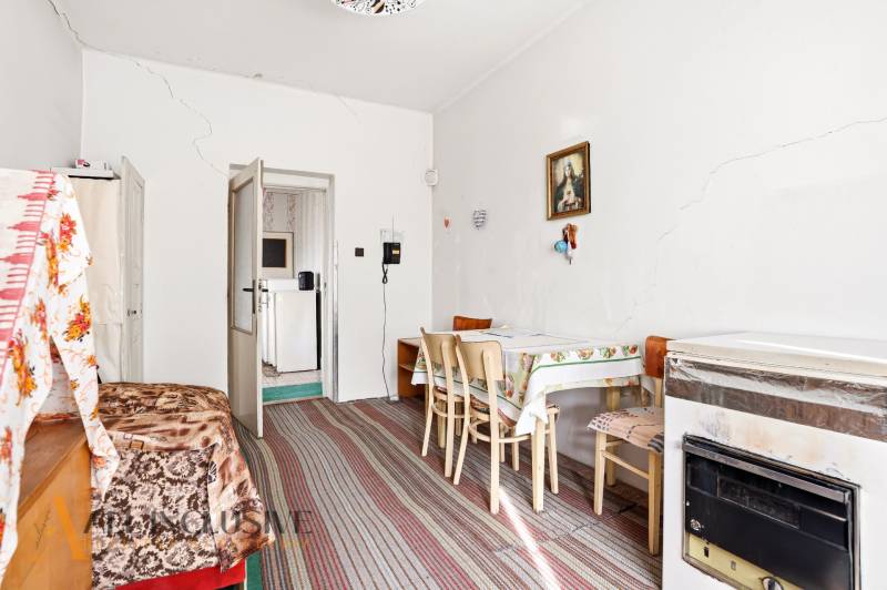 Dining room in a family house with white walls, a painting, a table, chairs, and a carpet.