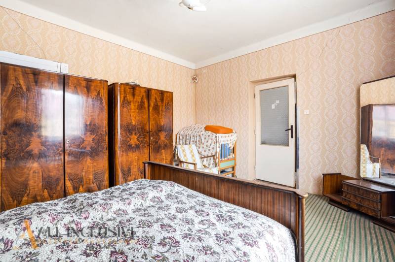 A bedroom in a family house with retro cabinets, a colorful carpet, and patterned wallpaper.