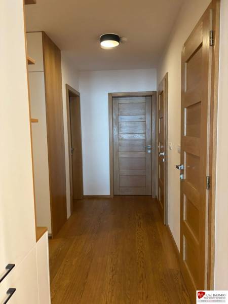 A bright hallway with doors and a wooden decor floor in a 3-room apartment.