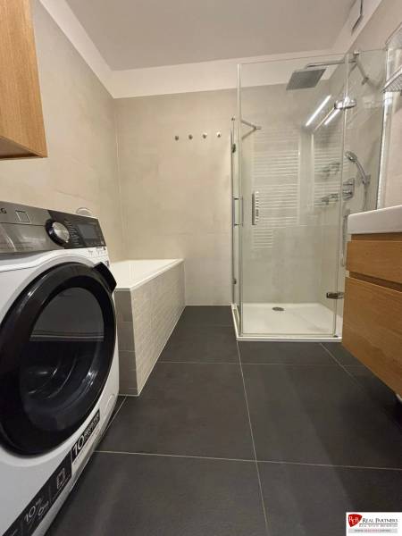 Bathroom with a shower, washing machine, and bathtub in a 3-room apartment.