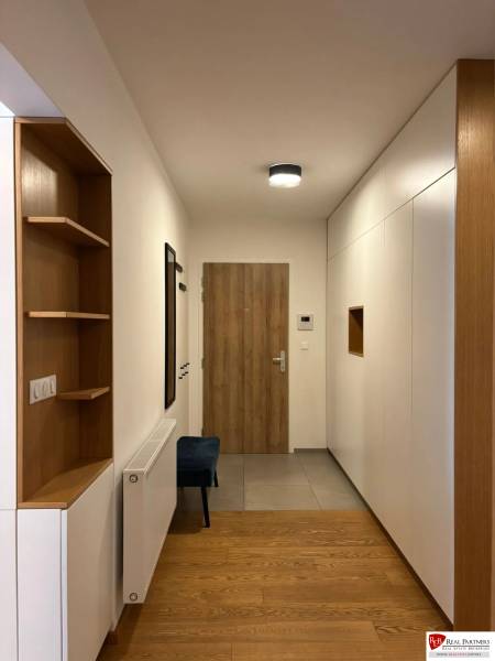 A hall in a 3-room apartment with a wooden decor floor and built-in wardrobes.