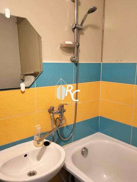 Bathroom in a 2-room apartment with colorful tiles and a mirror above the sink.