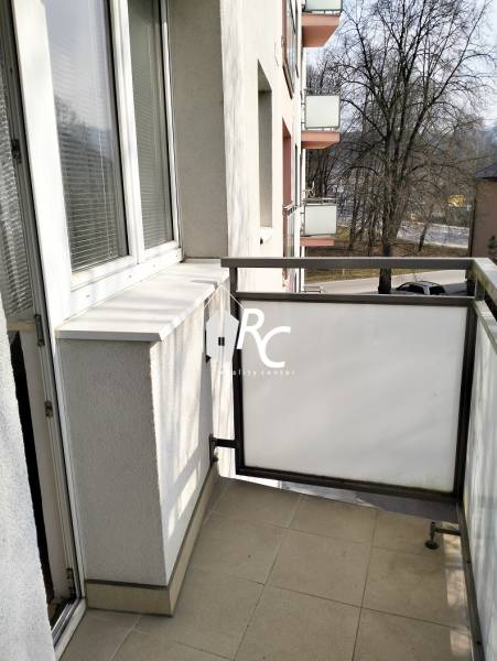 The balcony of a 2-room apartment on Hviezdoslavova Street in Čadca with a view of the street and trees.