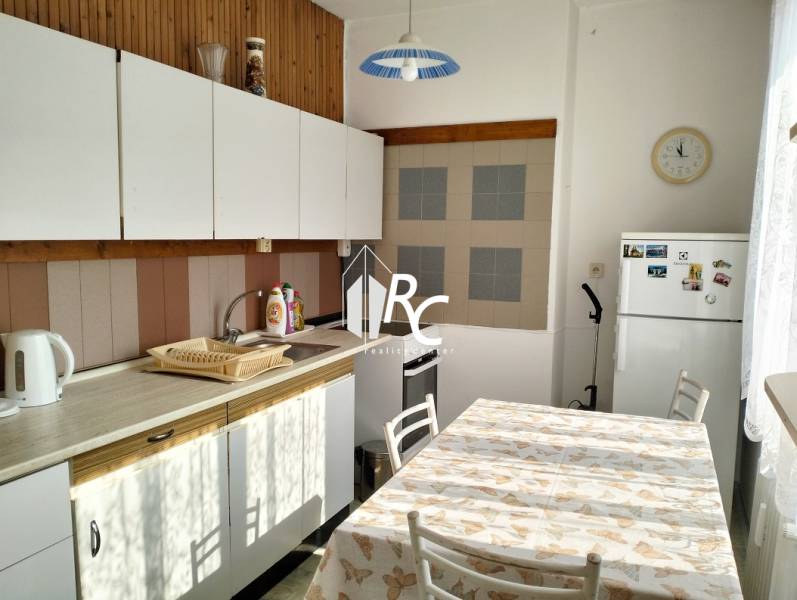 A kitchen in a 2-room apartment with a white kitchen unit and a dining table.