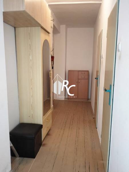 A hallway in a 2-room apartment with a wooden decor floor and built-in wardrobes.