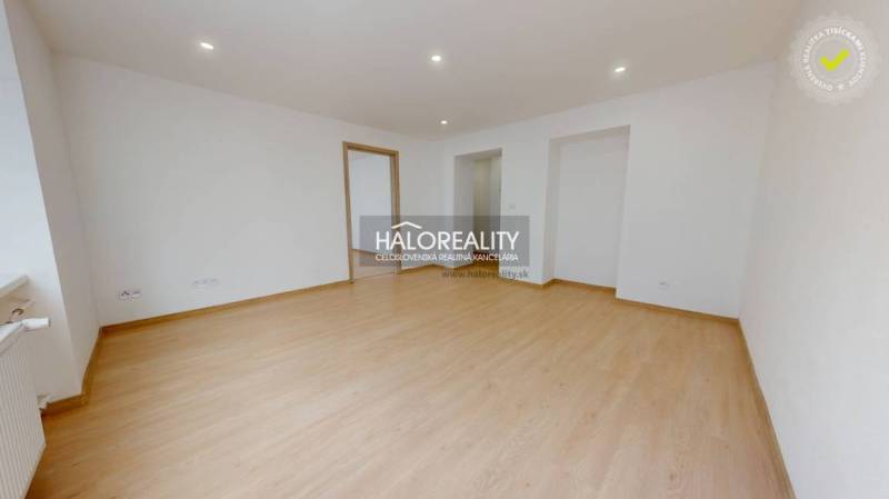 A room with a wooden decor floor in a 2-room apartment, white walls, entrance door.