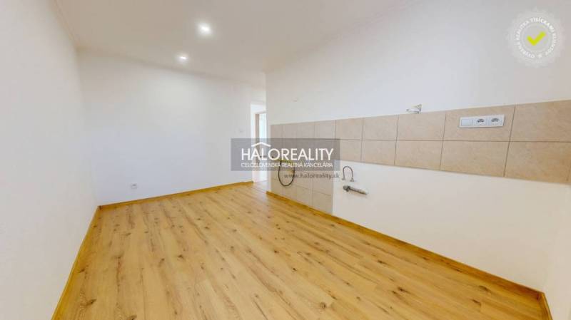 Bright kitchen in a 2-room apartment with a wooden decor floor and white walls.