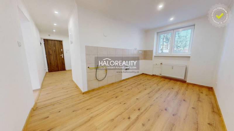 Interior of a 2-room apartment with a wooden decor floor and an empty kitchen.