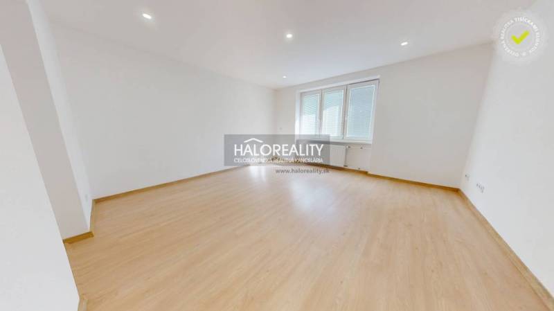 A spacious room in a 2-room apartment with a wood-patterned floor and a large window.