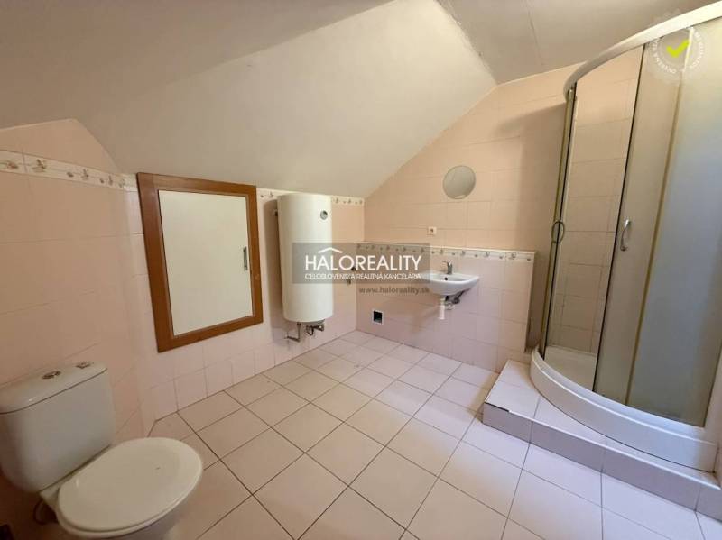 A bathroom in a studio apartment with a shower, sink, and toilet.