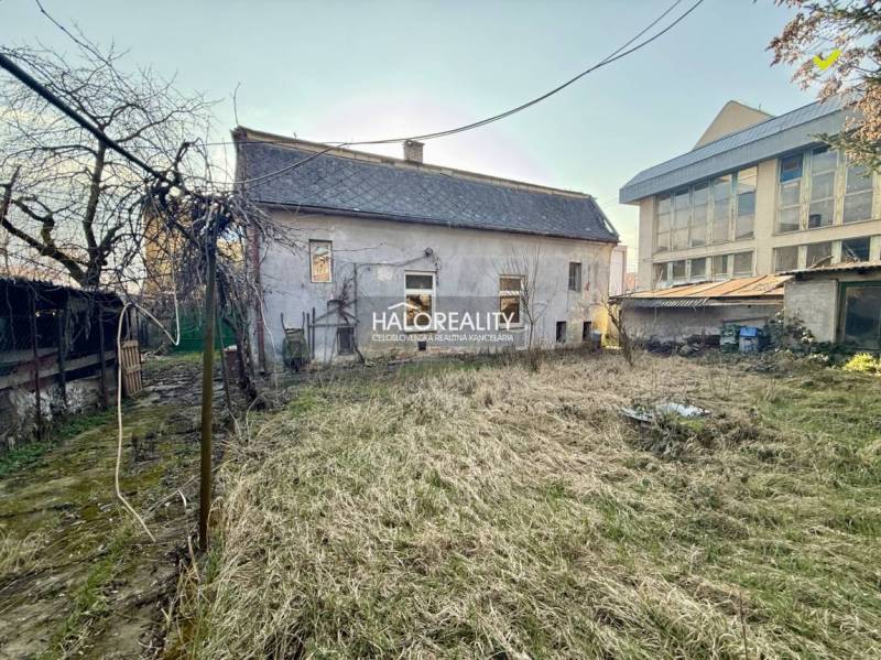 A garden and an unmaintained family house in Rimavská Sobota with surrounding trees.