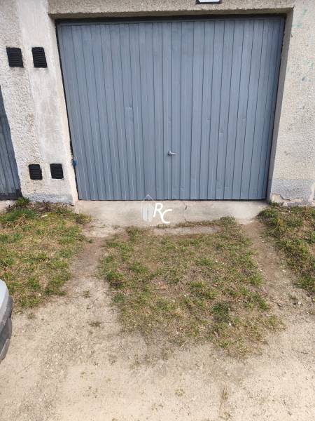 Garages on Kozmonautov Street in Martin with gray metal doors and a grassy edge.