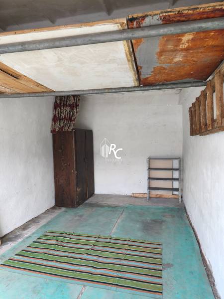 The interior of the garage includes a wooden cabinet, a rug, and empty shelves.