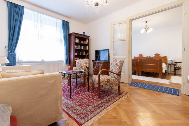 Living room in a 3-room apartment with a decorative carpet and wooden decor flooring.
