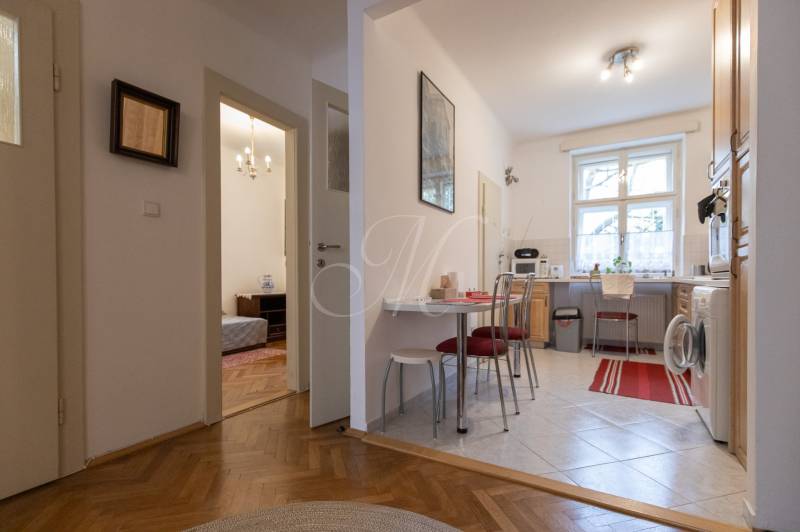 A kitchen with dining area, access to a room, and a floor with a wooden decor in a 3-room apartment.