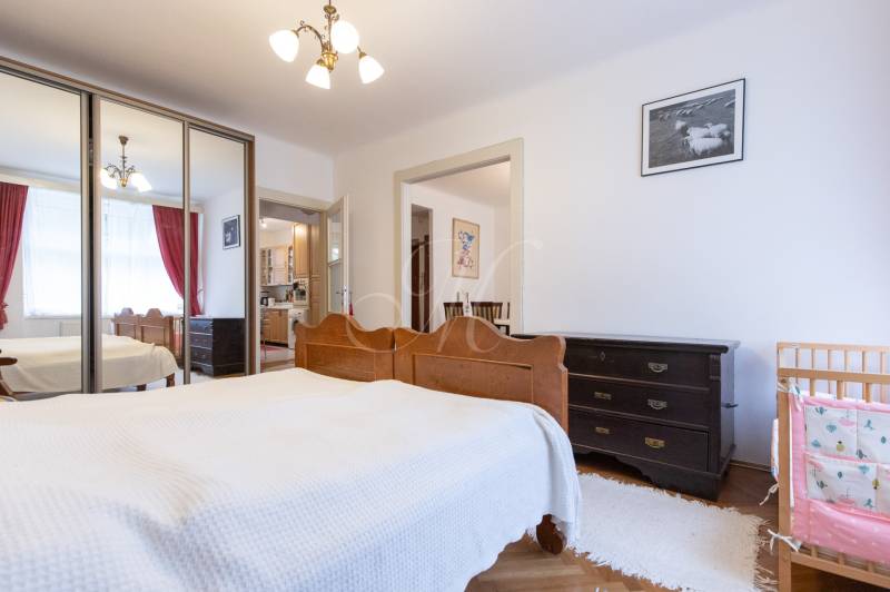 A bedroom with a large wardrobe, wooden furniture, and a small crib in a 3-room apartment.