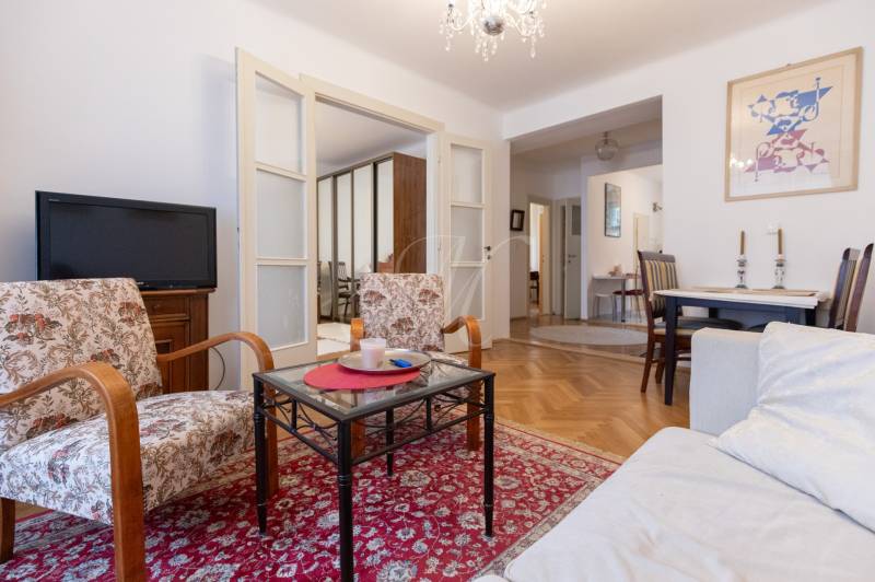 Living room in a 3-room apartment with carpets, floral armchairs, and a wooden decor floor.