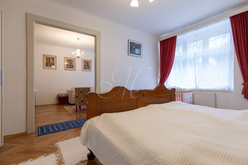A bedroom with a wooden bed in a 3-room apartment and a floor with a wooden decor.