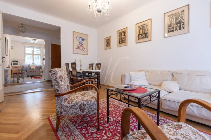 Living room with a sofa, armchairs, and a wooden decor floor in a three-room apartment.