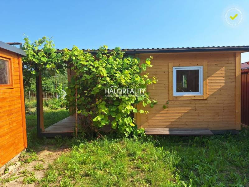 Wooden garden house with a terrace in the Gardens of Bojnice surrounded by greenery.