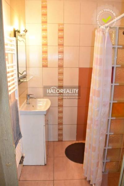 A bathroom in a 2-room apartment with a sink, shower, and ceramic tiles.
