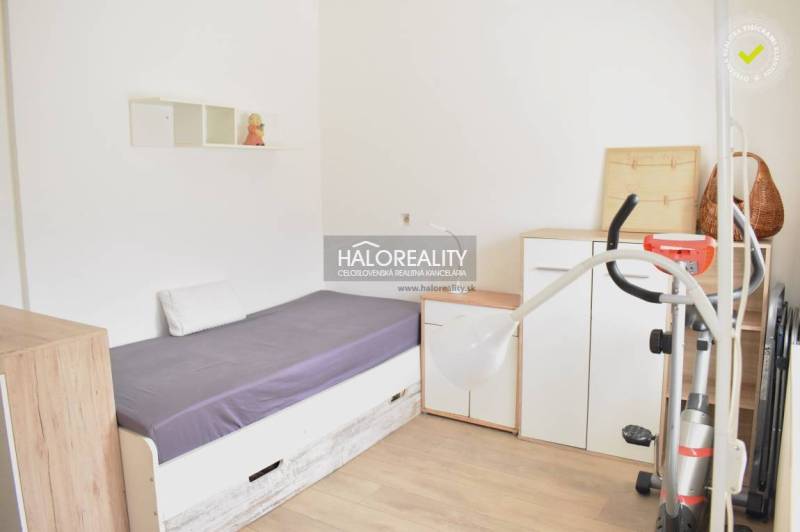 A simply furnished room with a bed, a wardrobe, and a floor with a wooden decor.