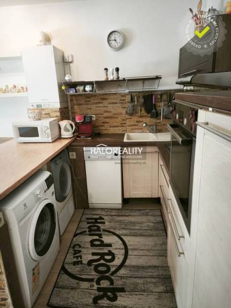 A kitchen in a 2-room apartment with a washing machine, microwave, and kitchen units.