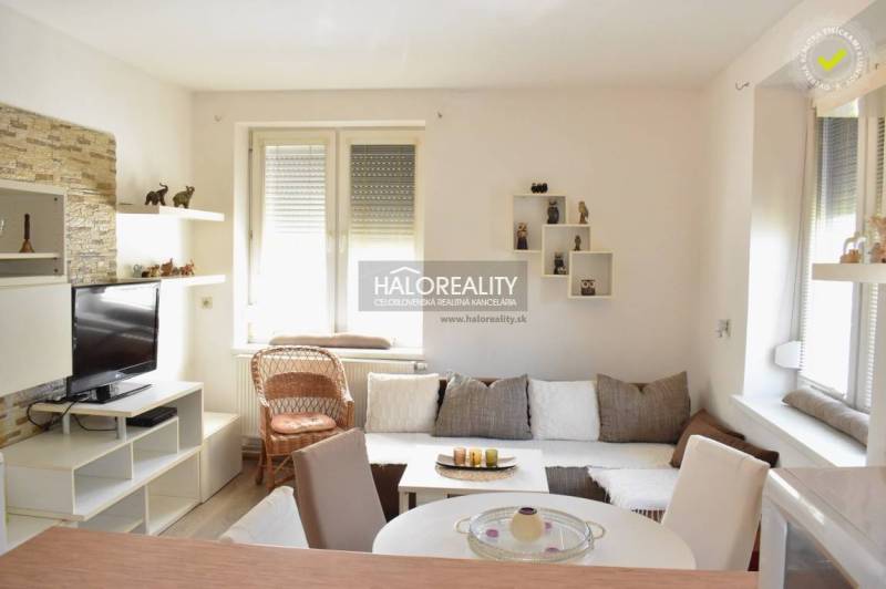 A bright living room with a TV, white furniture, and a sofa in a 2-room apartment.