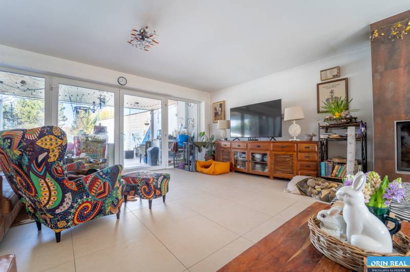 Living room in a family house with colorful armchairs and a large television on a dresser.
