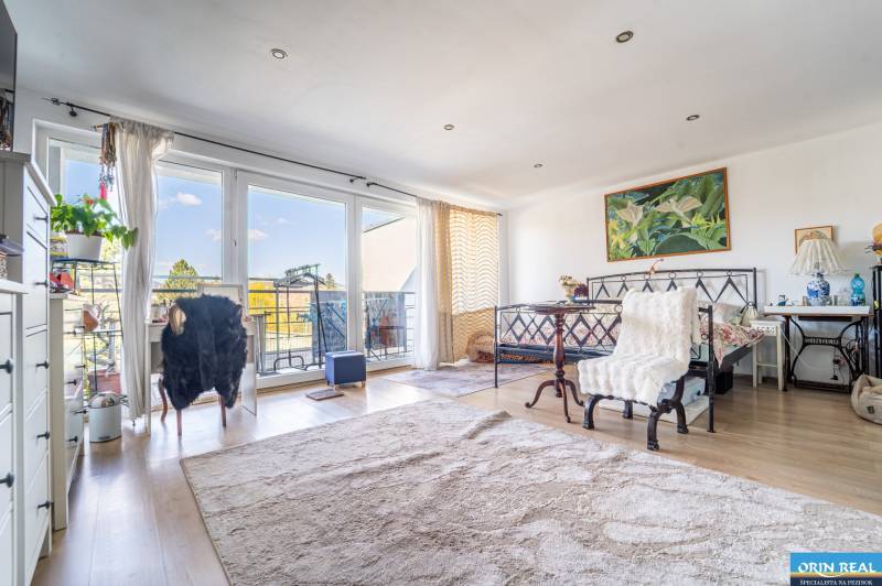 Living room with large windows, wood-patterned flooring, and comfortable seating in a family house.