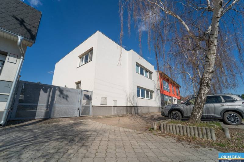 A family house on Bratislavská Street in Pezinok with a paved yard and a silver car.