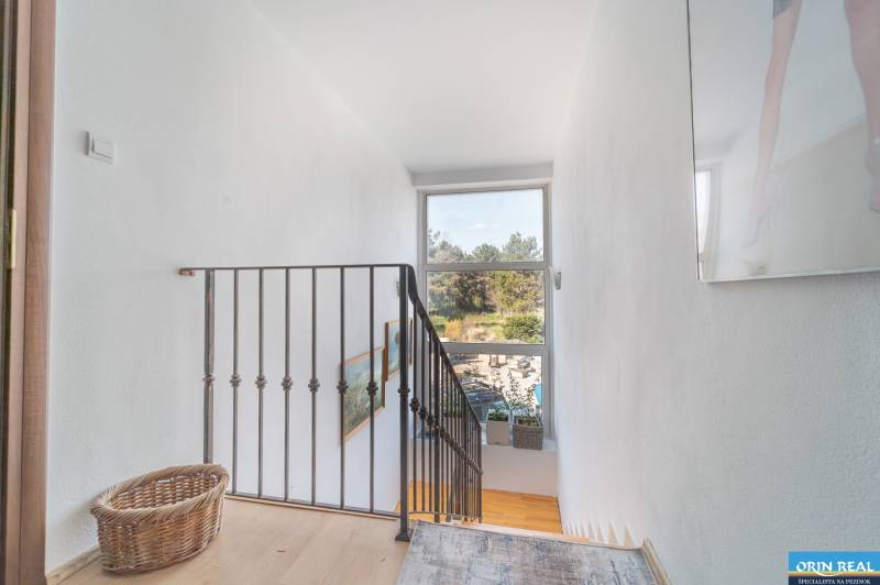 A staircase with a metal railing and a window, a floor with a wooden decor, family house.
