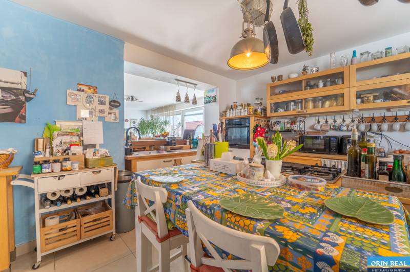 A kitchen in a family house with a colorful tablecloth and kitchen utensils on the shelves.