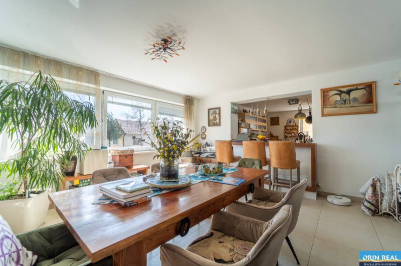 Dining area with a wooden table in a family house, decorated with flowers and plants.