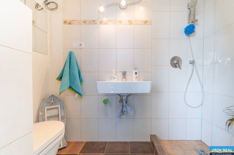A bathroom in a family house with a shower, a sink, and white tiles.