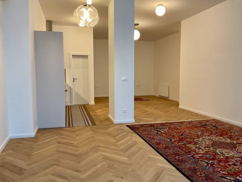 Living room in a two-room apartment with a wooden decor floor and oriental rugs.