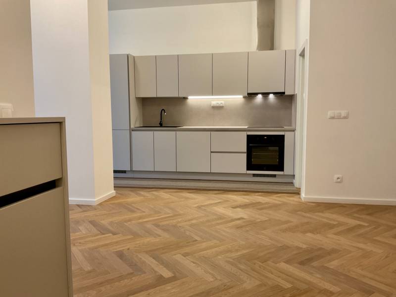 A kitchen in a 2-room apartment with a wood-patterned floor and light cabinets.