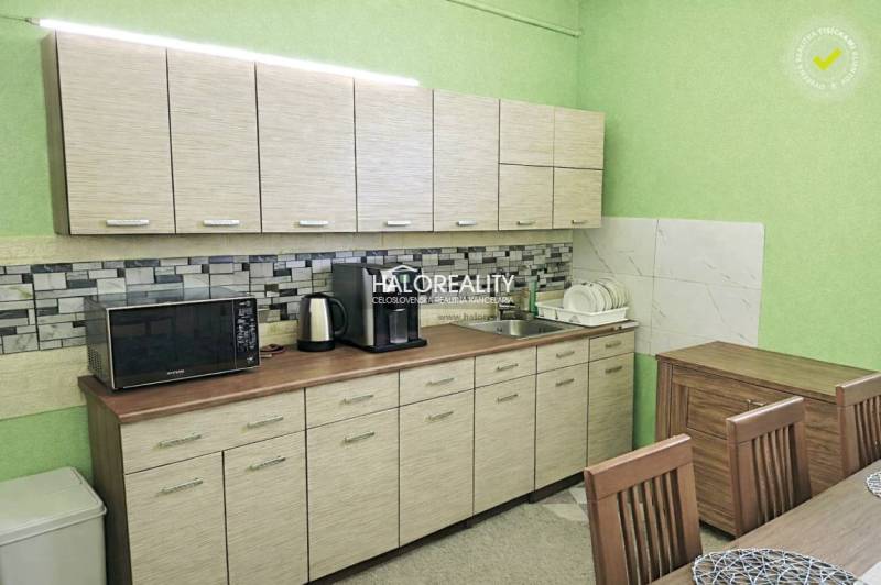 A kitchen in a family house with light furniture, a microwave, and dishes by the sink.