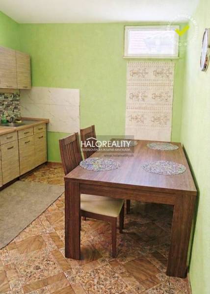 Interior of a family house with green walls, a kitchen unit, and a wooden table with placemats.
