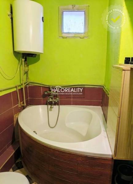 A bathroom in a family house with a corner bathtub and a bright green wall.