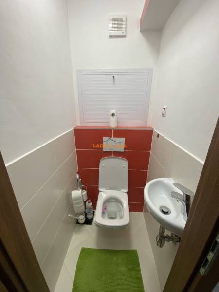 A small toilet with a sink in a 3-room apartment, equipped with white and red tiles.