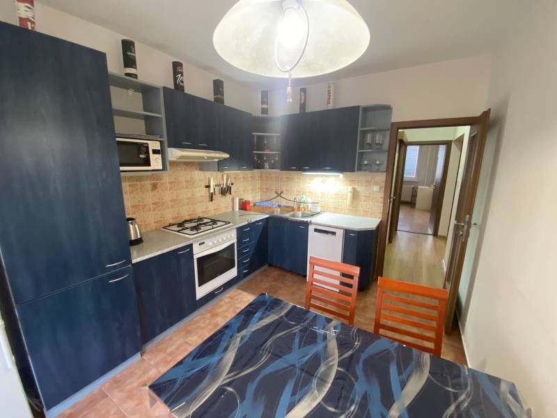 A kitchen in a 3-room apartment with blue cabinets and a dining table.