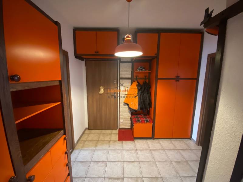 The hallway in a 3-room apartment with orange cabinets and tiled flooring.