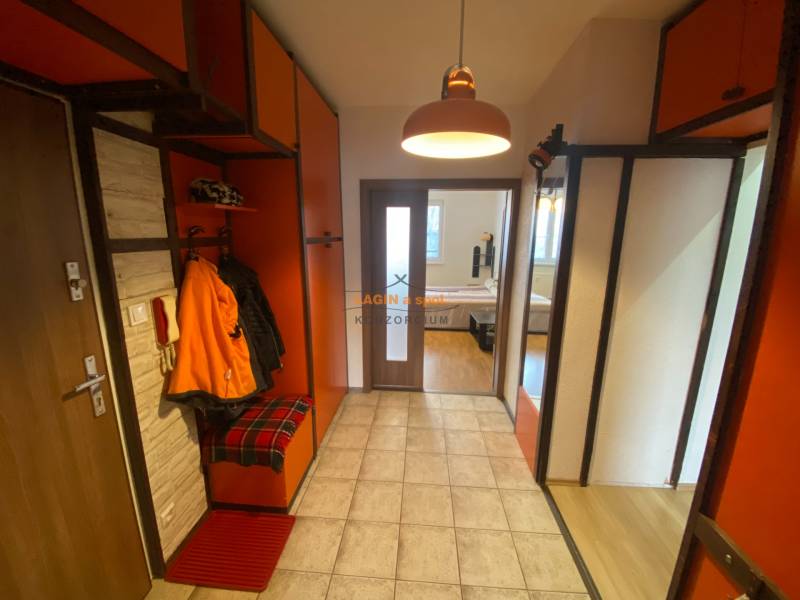 The entrance hall of a 3-room apartment with orange cabinets and tiles.