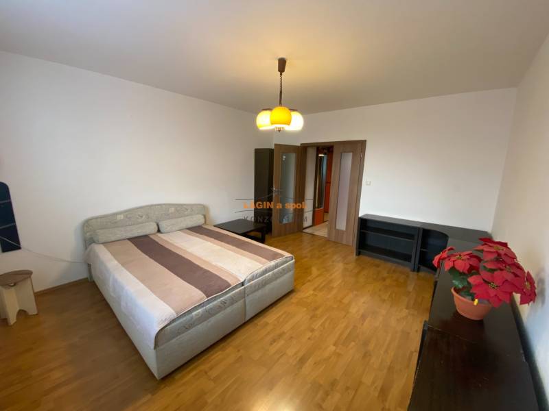 A bedroom with a double bed, wooden decor flooring, and furniture in a 3-room apartment.